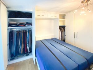 Linker Kleiderschrank geöffnet mit Bett